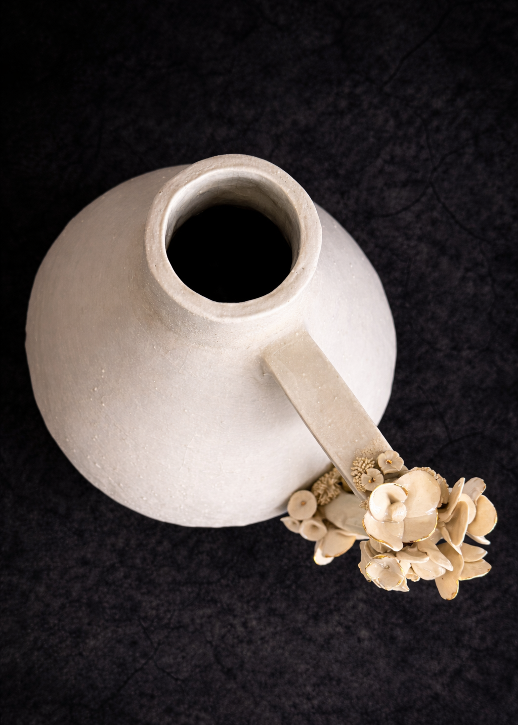 White ceramic pitcher with decorative handle on a dark background