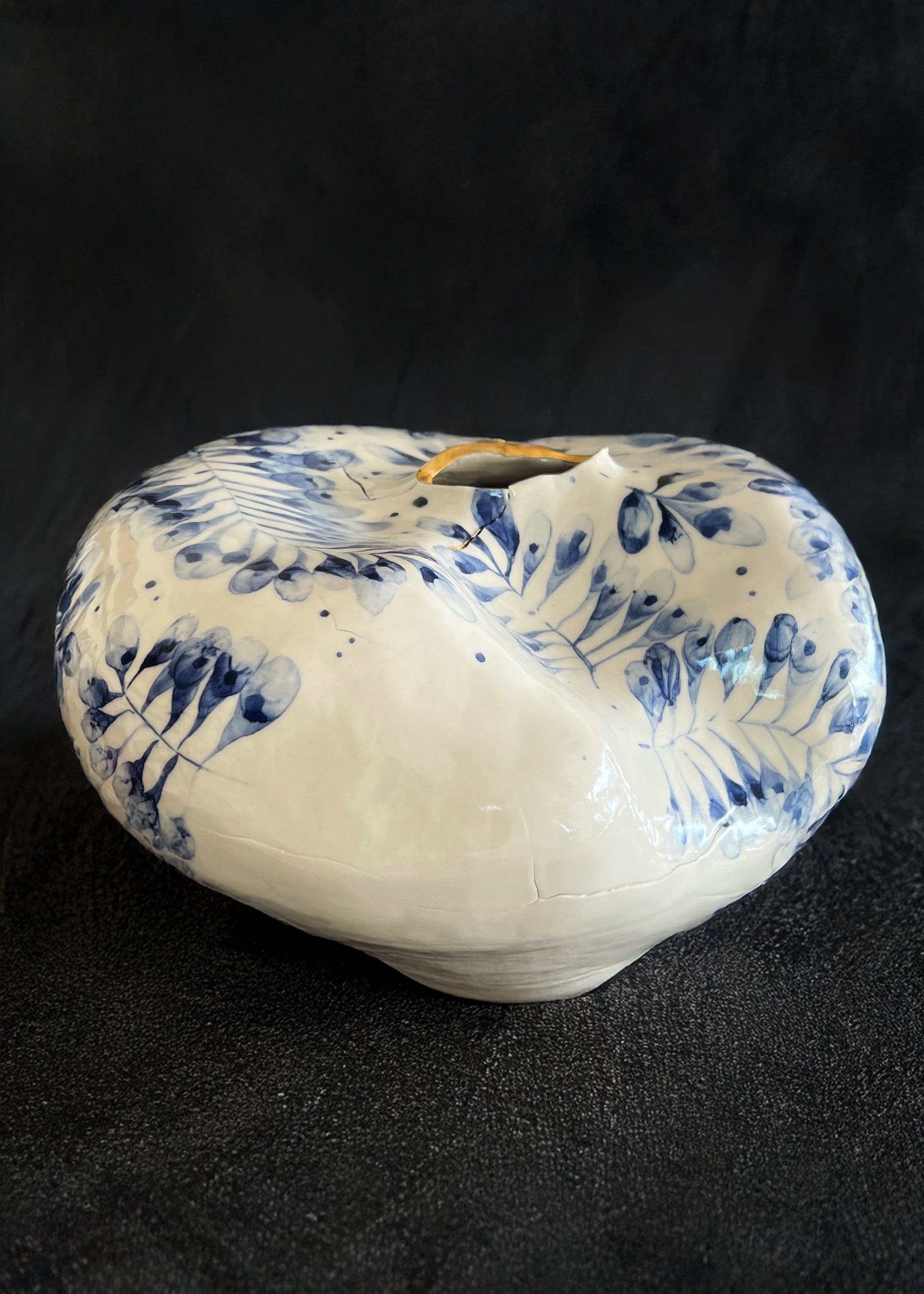 Porcelain piece with blue floral patterns and gold luster on a black background