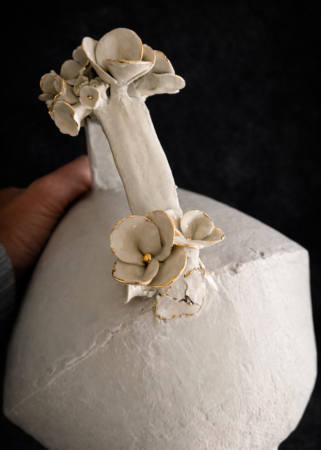 White ceramic vase with floral decorations on a dark background